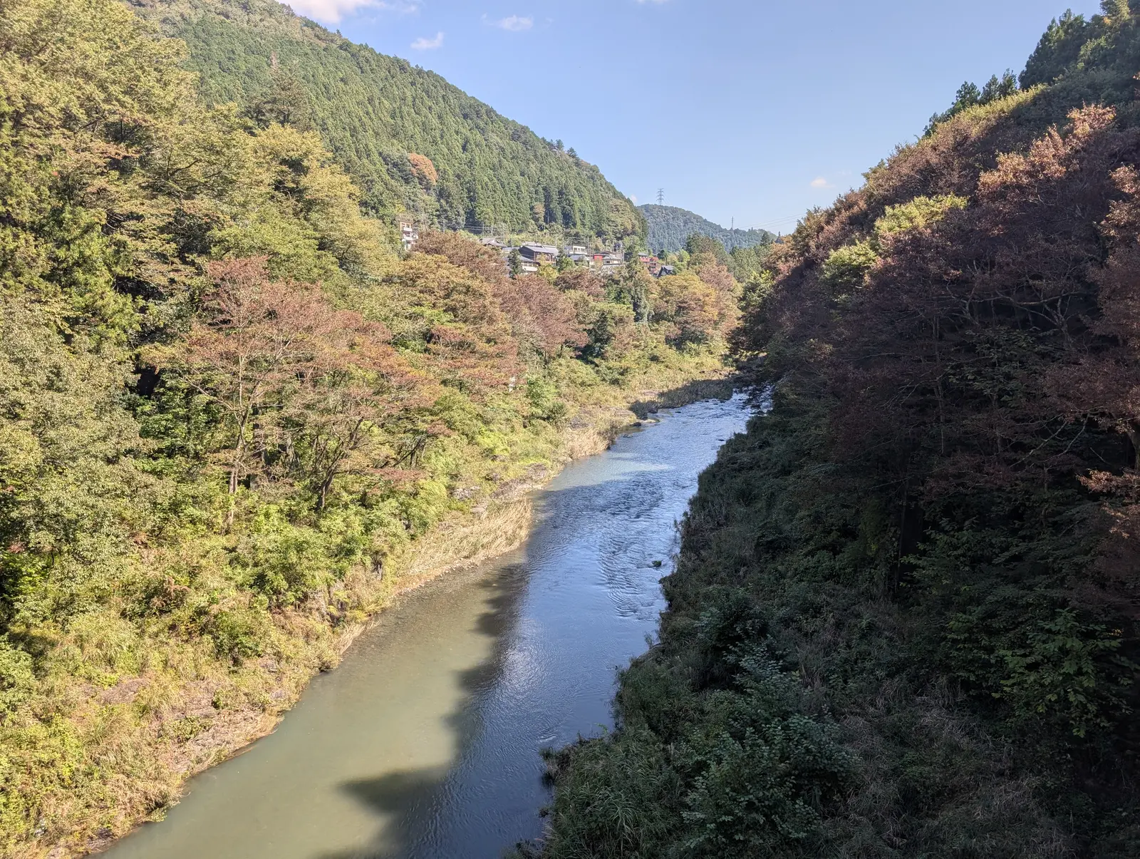 高い位置から撮った蛇行する川の谷。左の斜面は影の中、右の斜面は日が当たって明るく、川筋が下から遠くへ延びている。